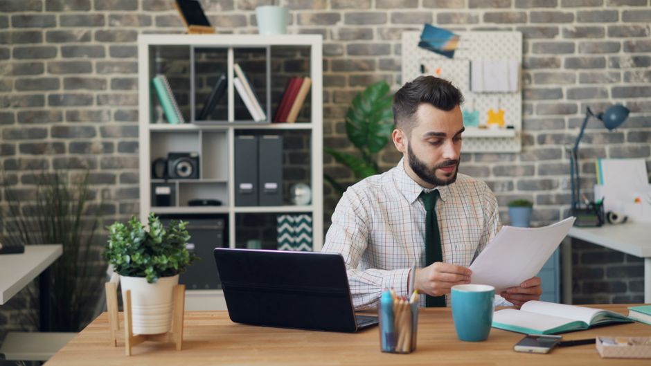 Joven leyendo documentos en su escritorio